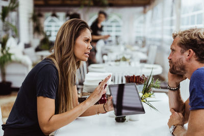 Female owner taking order from customer while using digital tablet in restaurant