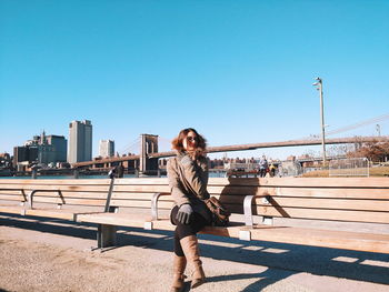 Portrait of smiling young woman standing against clear sky on sunny day