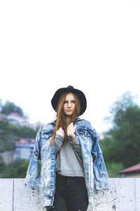 Portrait of smiling young woman standing against sky