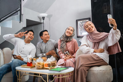 Portrait of friends using mobile phone while sitting on table