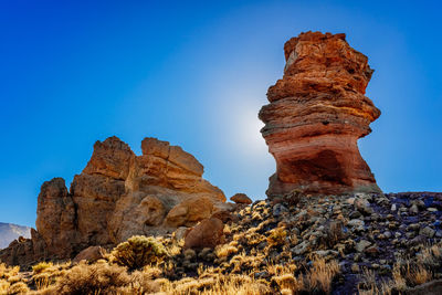 Low angle view of rock formations against clear blue sky