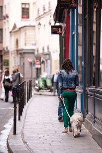 Rear view of woman with dog walking on street