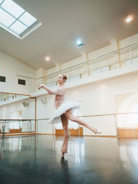 Mid adult ballerina dancing on floor
