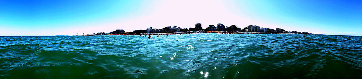 People on sea shore against clear sky