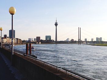 View of bridge over river by buildings against sky