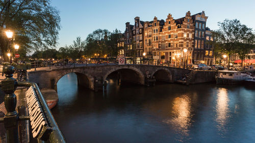 Arch bridge over canal against sky in city