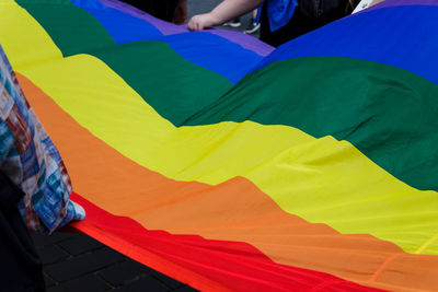 Midsection of people holding rainbow flag