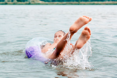 The girl pinches her nose and falls out of the inflatable ring into the river. local tourism. 