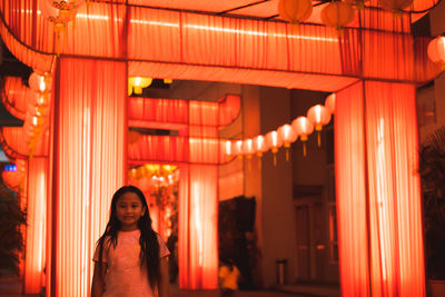 Portrait of girl standing against illuminated decoration