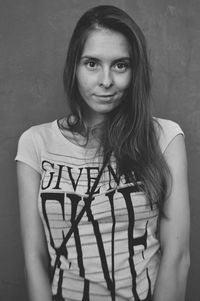 Portrait of young woman standing against wall