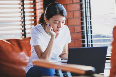 Young woman using mobile phone while sitting on table