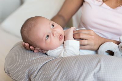 Midsection of mother with son sitting on sofa at home