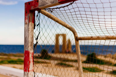 Close-up of fence by sea against sky