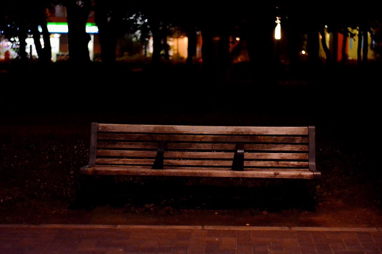 night, illuminated, built structure, architecture, dark, religion, silhouette, wood - material, tree, spirituality, place of worship, outdoors, no people, bench, architectural column, park - man made space, light - natural phenomenon, building exterior, tranquility, glowing