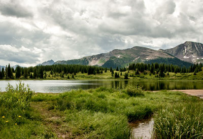 Scenic view of river by mountains against cloudy sky