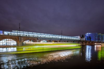 Blurred image of boat in spree river against railroad station at night