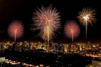 Firework display over illuminated buildings in city at night