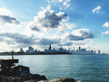 Sea by buildings in city against sky