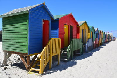 Row of houses on beach against clear blue sky