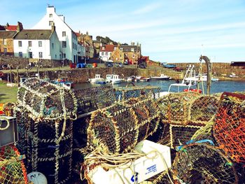 Fishing boats moored at harbor against sky