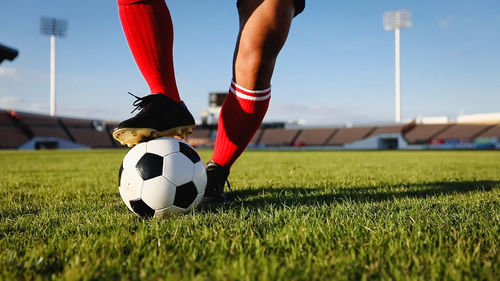 Low section of man playing soccer at stadium