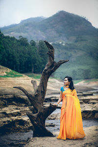 Full length of woman standing by tree against mountain