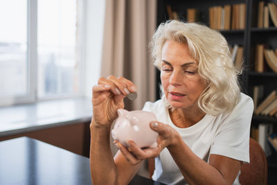 Side view of young woman holding piggy bank