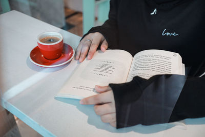 Midsection of woman reading book on table