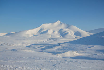 Snowcapped landscape against clear blue sky