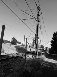 Electricity pylons on field against clear sky