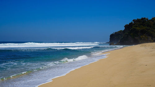 Scenic view of beach against clear blue sky