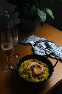 A plate of spanish paella prepared for two accompanied by two glasses