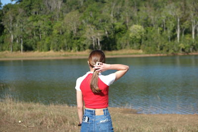Side view of young woman standing by lake