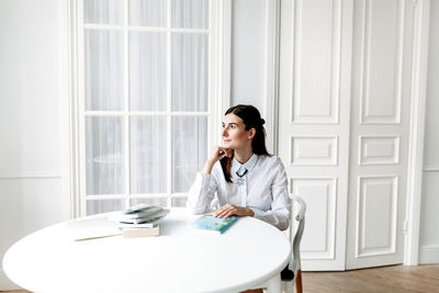 Young woman sitting on table at home