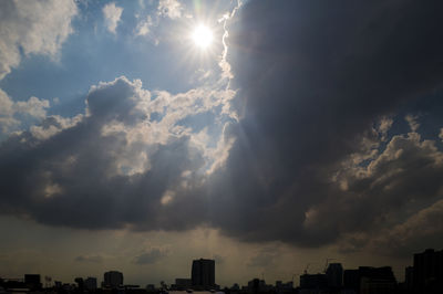 Low angle view of sunlight streaming through clouds in sky