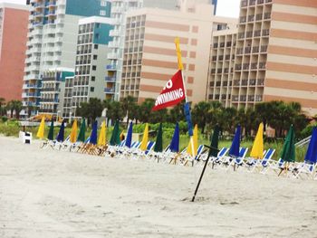 Flags on beach against city