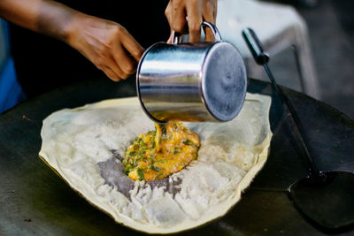 Cropped hands preparing food on pan