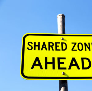 Low angle view of road sign against clear blue sky