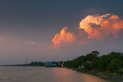 Scenic view of trees by building against sky during sunset