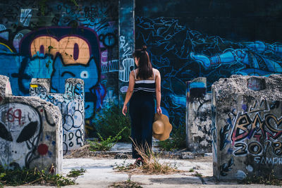 Woman standing by graffiti on wall