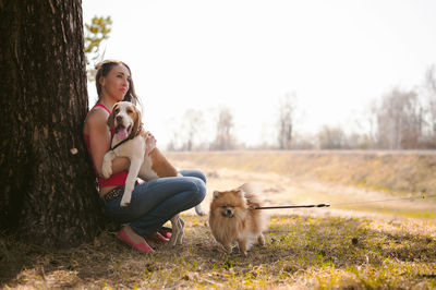 Side view of woman crouching with dogs at park