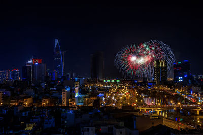 Firework display over illuminated buildings in city at night