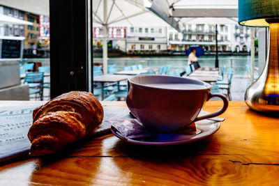 Close-up of coffee cup with croissant on table in restaurant