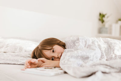 An adorable little boy is lying on the bed looking thoughtful or sad. children's sleep problems