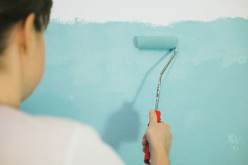 Rear view of person painting wall