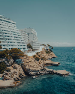 Buildings by sea against clear sky