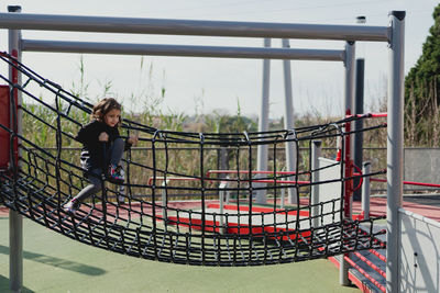 Four-year-old girl playing in the park, climbing in the daytime.