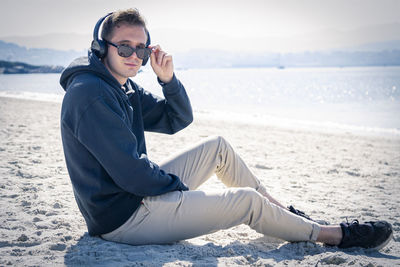 Young man on the beach relaxing with headphones
