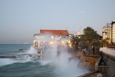Scenic view of sea against buildings at dusk