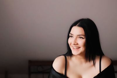 Portrait of a smiling young woman against wall